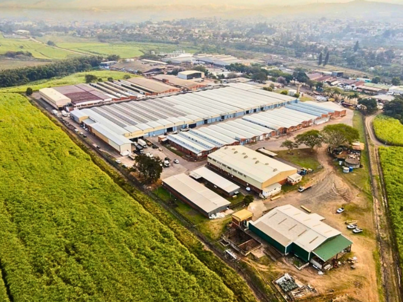 Aerial view of a large industrial warehouse complex featuring multiple connected buildings, metal roofing, and extensive surrounding land in a rural setting.