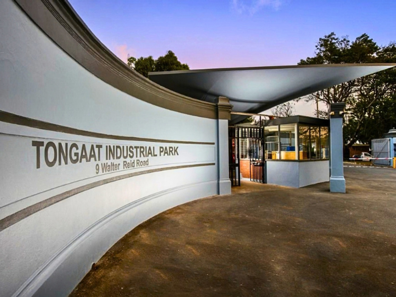 The main entrance to Tongaat Industrial Park, featuring a modern curved boundary wall, security gatehouse, and cantilevered roof structure.