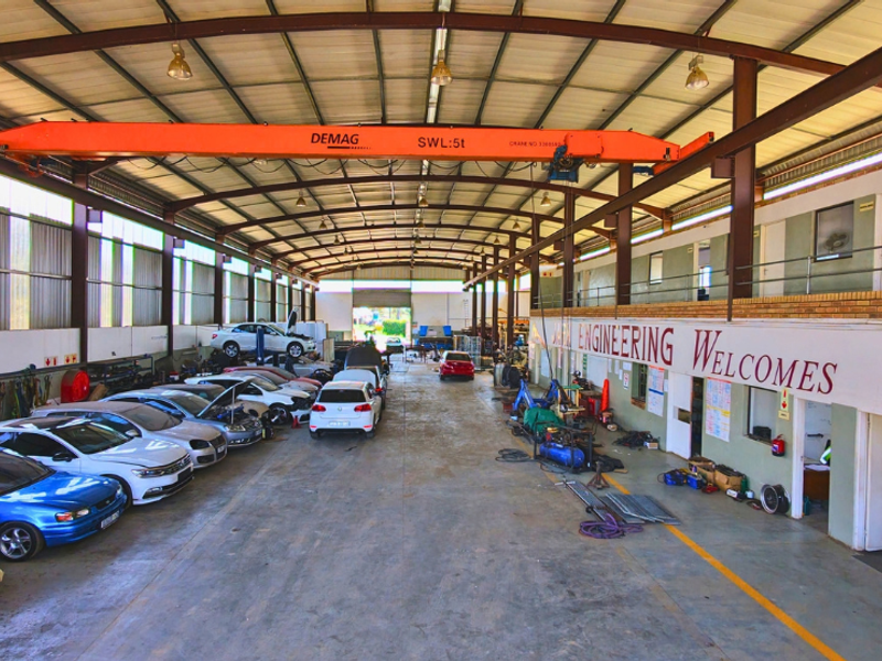 Spacious industrial workshop featuring a high-clearance steel structure, overhead 5-ton gantry crane, concrete flooring, and an integrated mezzanine office or storage level.