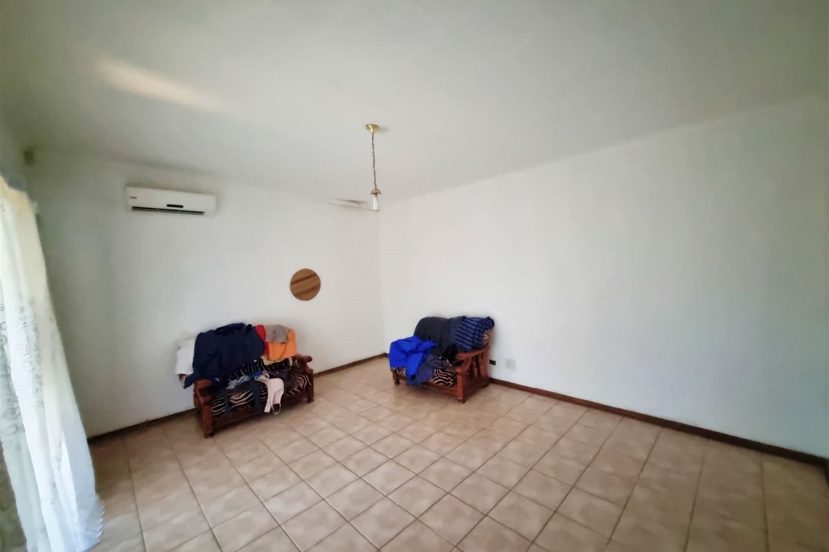 A living room featuring ceramic floor tiles, a wall-mounted split-system air conditioner, and neutral wall finishes.