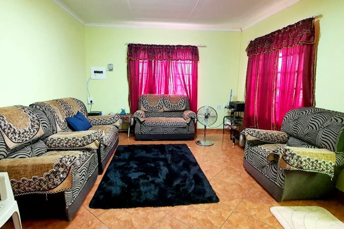 A living room featuring tiled flooring and dual windows with curtains, providing a functional space for relaxation.