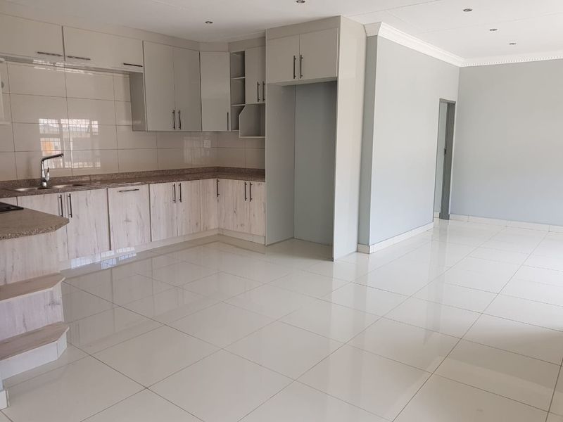 A bright, open-plan kitchen and living area featuring modern cabinetry, granite countertops, and polished tiled flooring throughout.