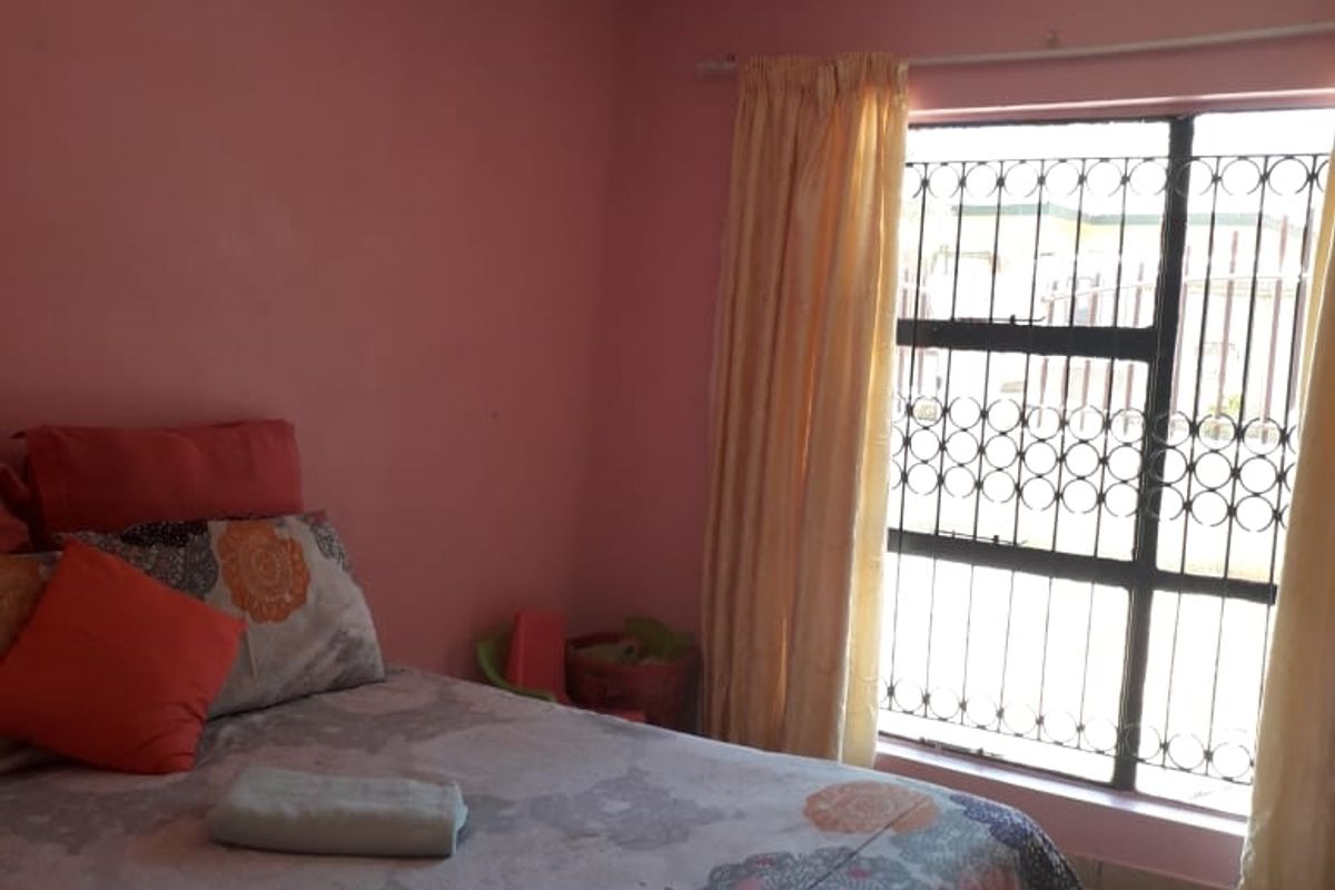 A bedroom featuring tiled flooring and a window fitted with a decorative security gate.