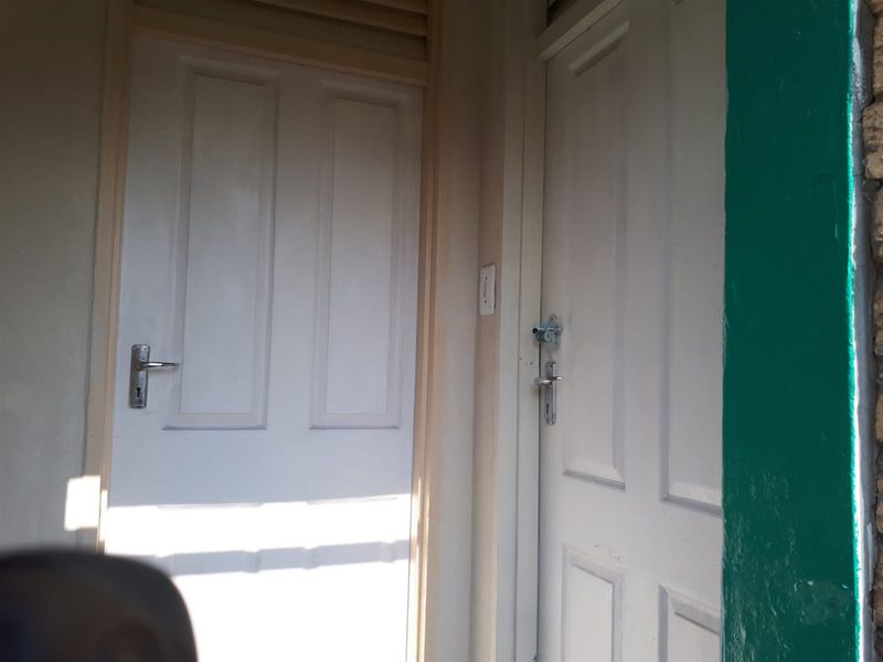 An exterior view of two panelled entrance doors with visible wear and paint deterioration on the surrounding frames.