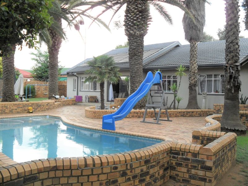 Outdoor pool area featuring brick paving, raised brick retaining walls, and a swimming pool set against the rear elevation of the house.