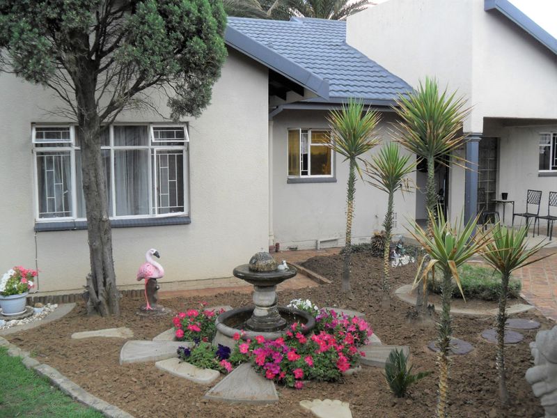 Rear garden area featuring a central stone fountain, paved patio space, and established landscaping against the house exterior.