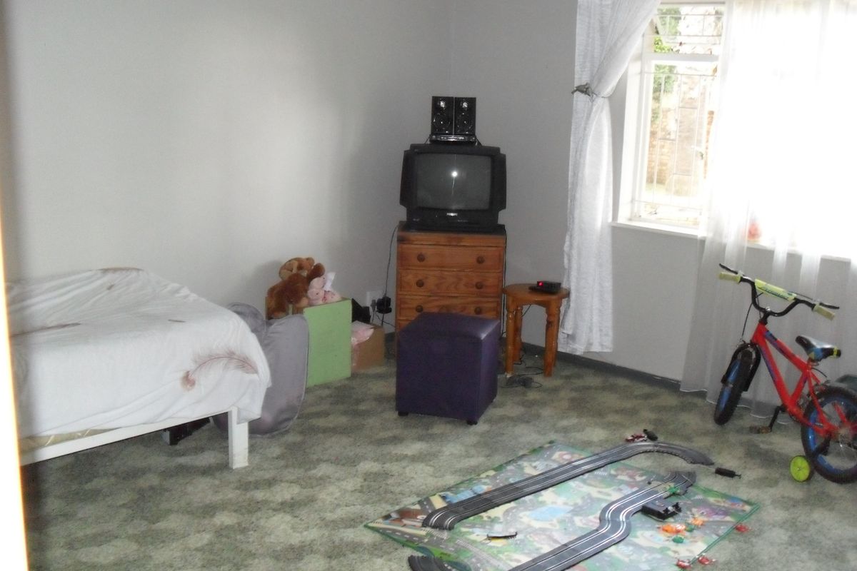 A bedroom featuring carpeted flooring and a window fitted with security bars.