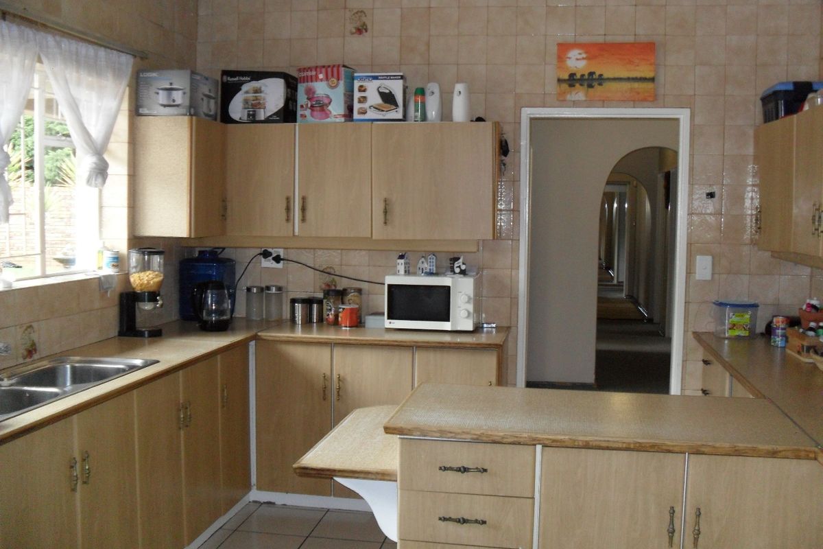 A dated kitchen featuring laminate cabinetry, tiled walls, and a double bowl sink, offering a functional layout with potential for modern renovation.