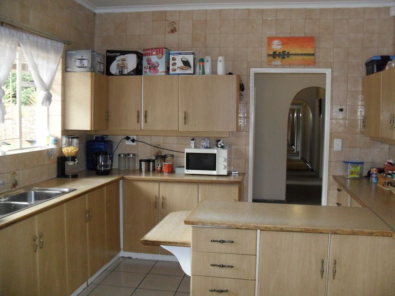 A dated kitchen featuring laminate cabinetry, tiled walls, and a double bowl sink, offering a functional layout with potential for modern renovation.