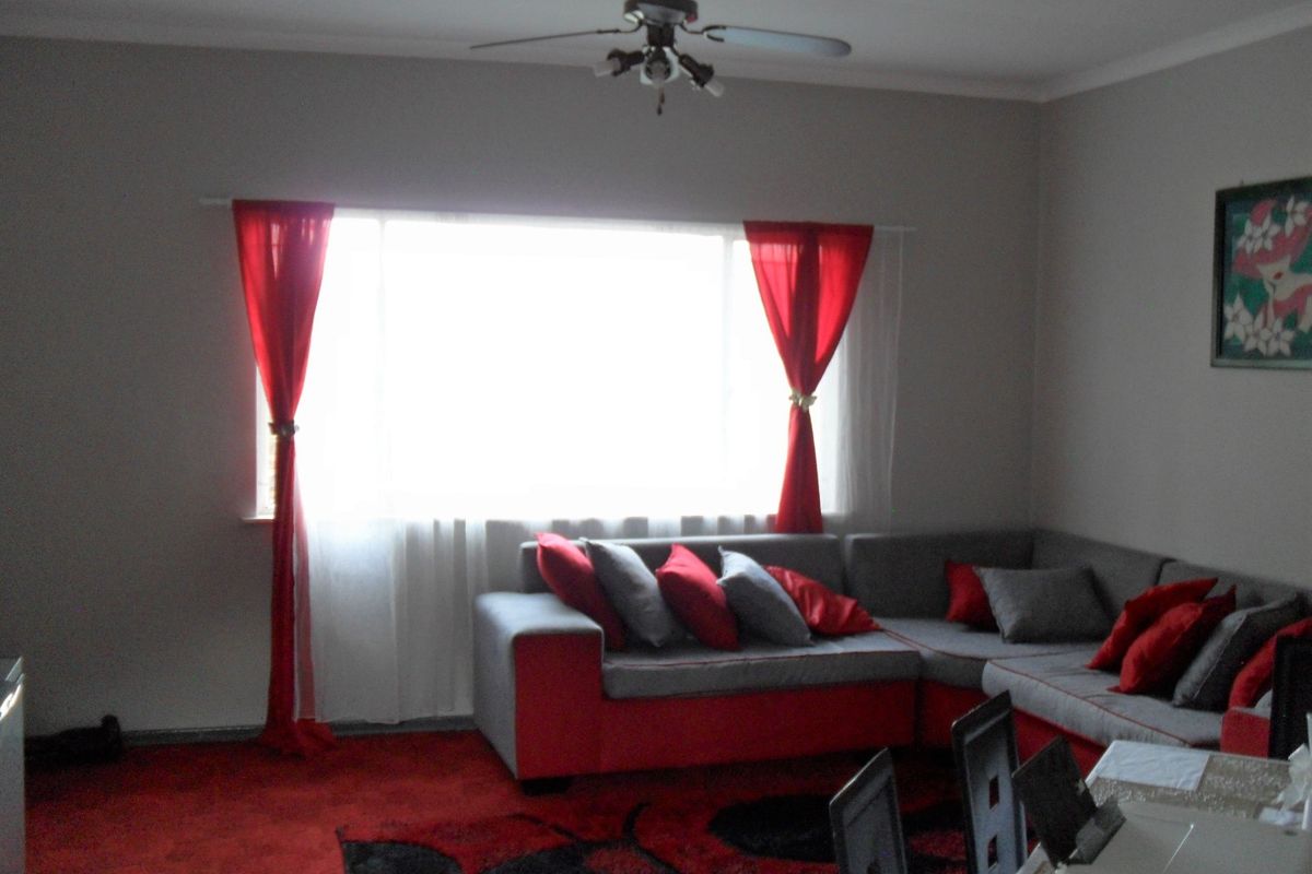 A living room featuring a ceiling fan and large window, providing a functional space for relaxation.