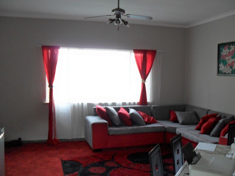 A living room featuring a ceiling fan and large window, providing a functional space for relaxation.