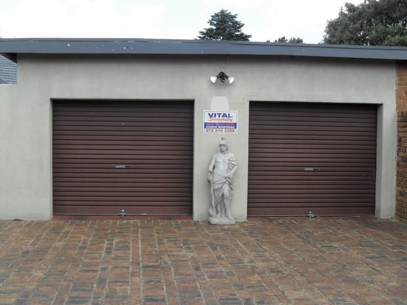 A double garage featuring brown roller doors and a brick-paved driveway, providing secure off-street parking.