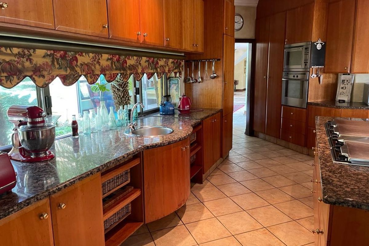 A spacious kitchen featuring extensive wooden cabinetry, granite countertops, built-in appliances, and ceramic floor tiles, offering a functional and traditional layout.