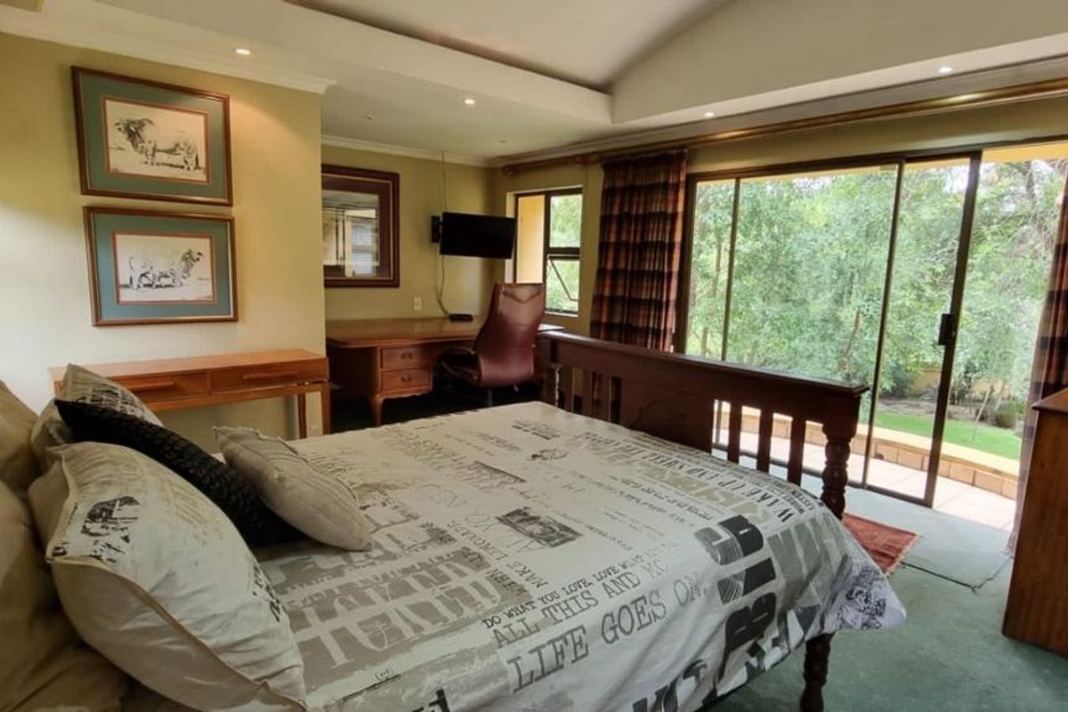 Spacious bedroom featuring a recessed ceiling, built-in desk area, and large sliding glass doors providing direct access to the outdoor garden space.