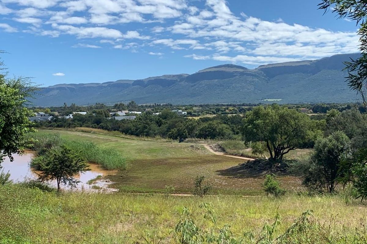 A scenic view of the surrounding landscape featuring natural vegetation, a water body, and a distant mountain range.