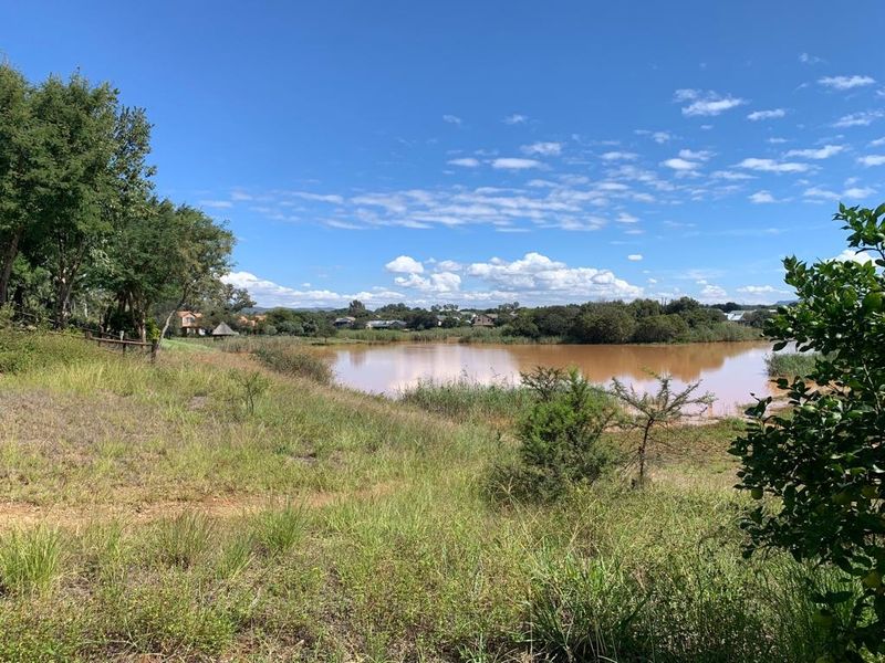 A scenic view of a natural lake surrounded by lush greenery and mature trees, showcasing the tranquil landscape of the vacant residential property.