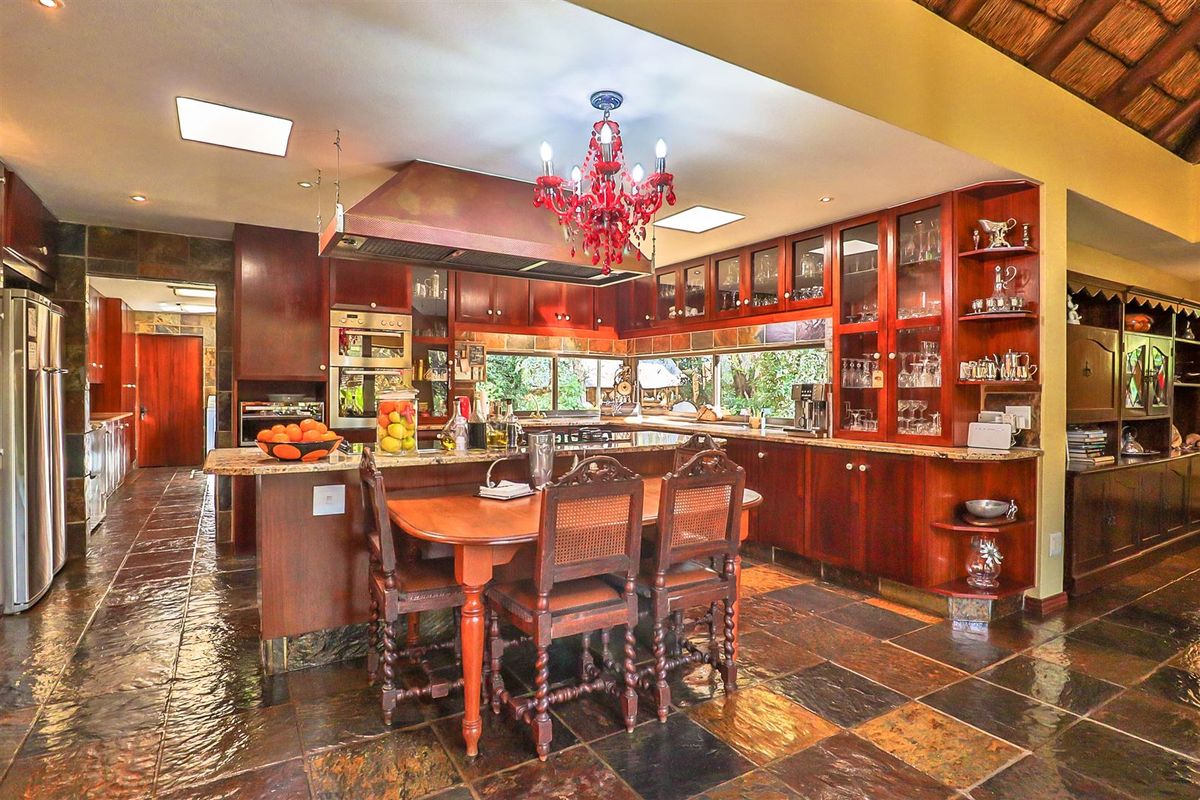 Spacious kitchen featuring dark wood cabinetry, granite countertops, slate flooring, and a built-in oven, offering a traditional aesthetic with ample storage and display space.
