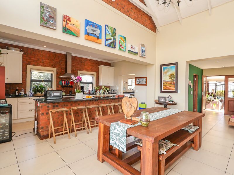 Spacious open-plan kitchen and dining area featuring vaulted ceilings, exposed brick accents, granite countertops, and large tiled flooring throughout.
