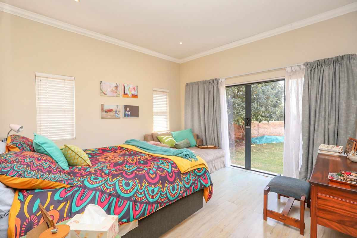 Spacious bedroom featuring laminate flooring, recessed lighting, and a large sliding glass door providing direct access to the rear garden.