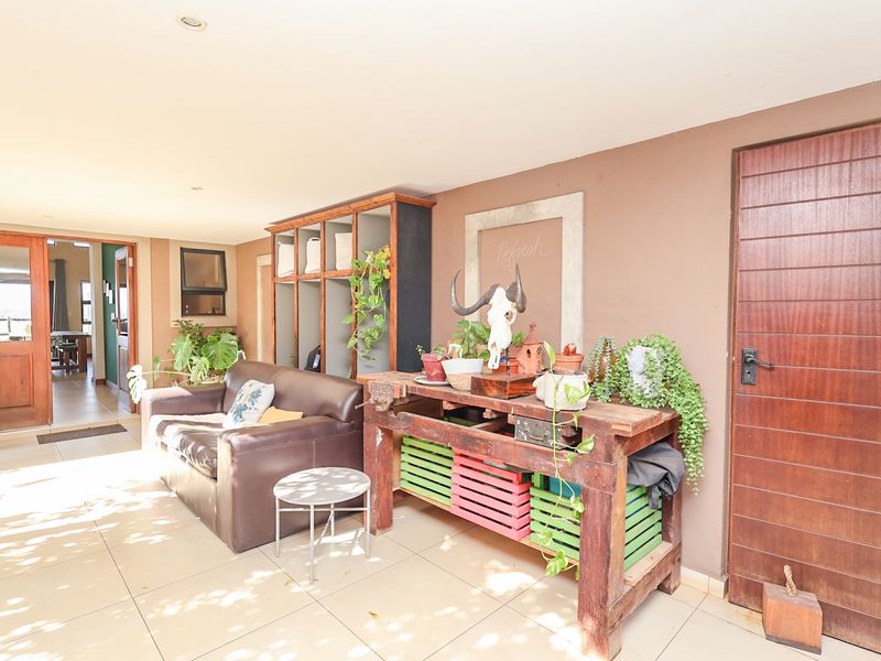 A covered patio area featuring tiled flooring, recessed lighting, and a built-in shelving unit, providing a functional outdoor living space.