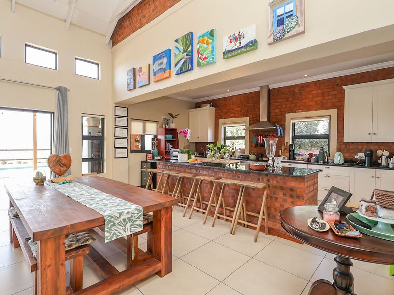 Spacious open-plan kitchen and dining area featuring exposed brick walls, vaulted ceilings with timber beams, and a large kitchen island with granite countertops.