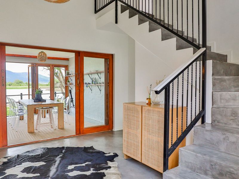 Modern living area featuring a striking concrete staircase with wrought iron railings, polished concrete floors, and large timber sliding doors opening to a patio.