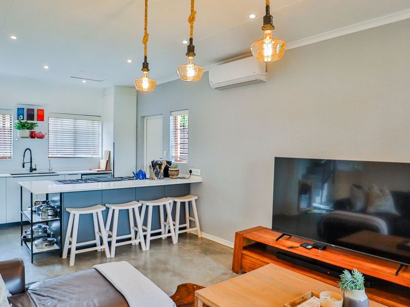 Modern open-plan living area featuring a sleek kitchen with a central island, polished concrete floors, and integrated air conditioning.
