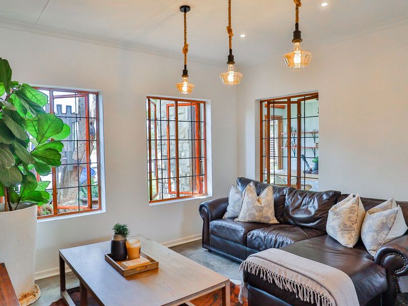 A bright and inviting living room featuring classic leaded glass windows with timber frames and stylish pendant lighting.