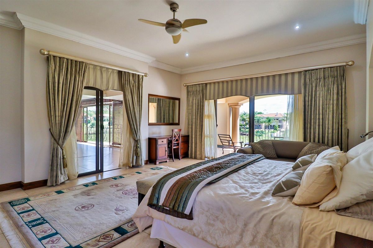 Spacious bedroom featuring tiled flooring, crown molding, a ceiling fan, and large sliding glass doors providing access to an outdoor patio area.
