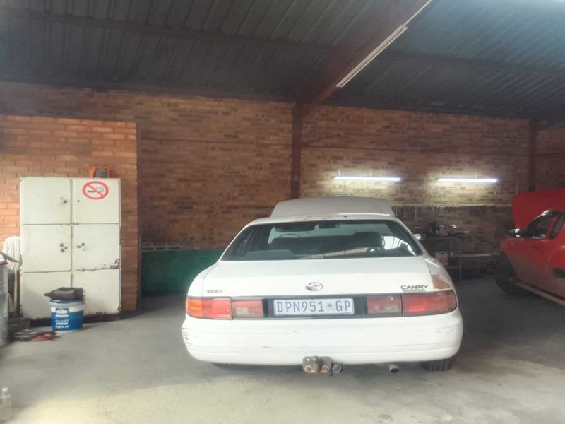 Spacious industrial workshop area featuring exposed brick walls, high ceilings, and functional lighting, suitable for automotive or light industrial operations.