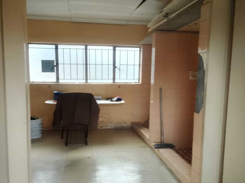 A dated utility or wash area featuring tiled walls, a built-in counter, and a raised tiled platform, requiring significant refurbishment and modernization.