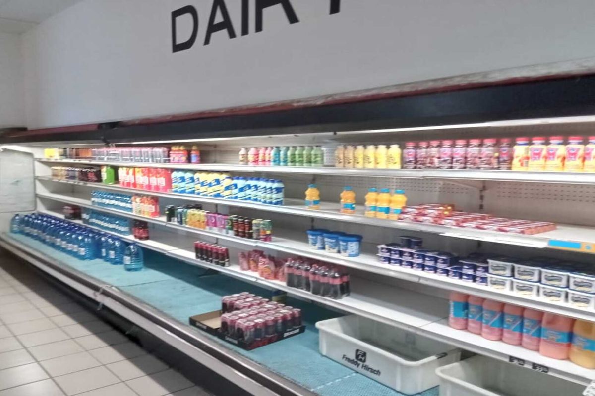 Commercial dairy refrigeration display unit featuring multiple shelves for product storage within a retail environment.