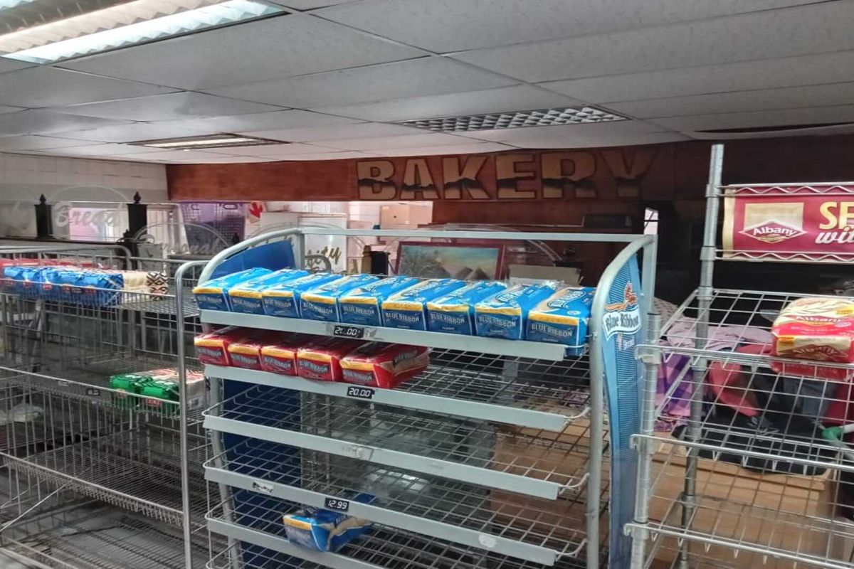Commercial bakery section featuring drop ceiling, fluorescent lighting, and metal shelving units for product display within a retail environment.