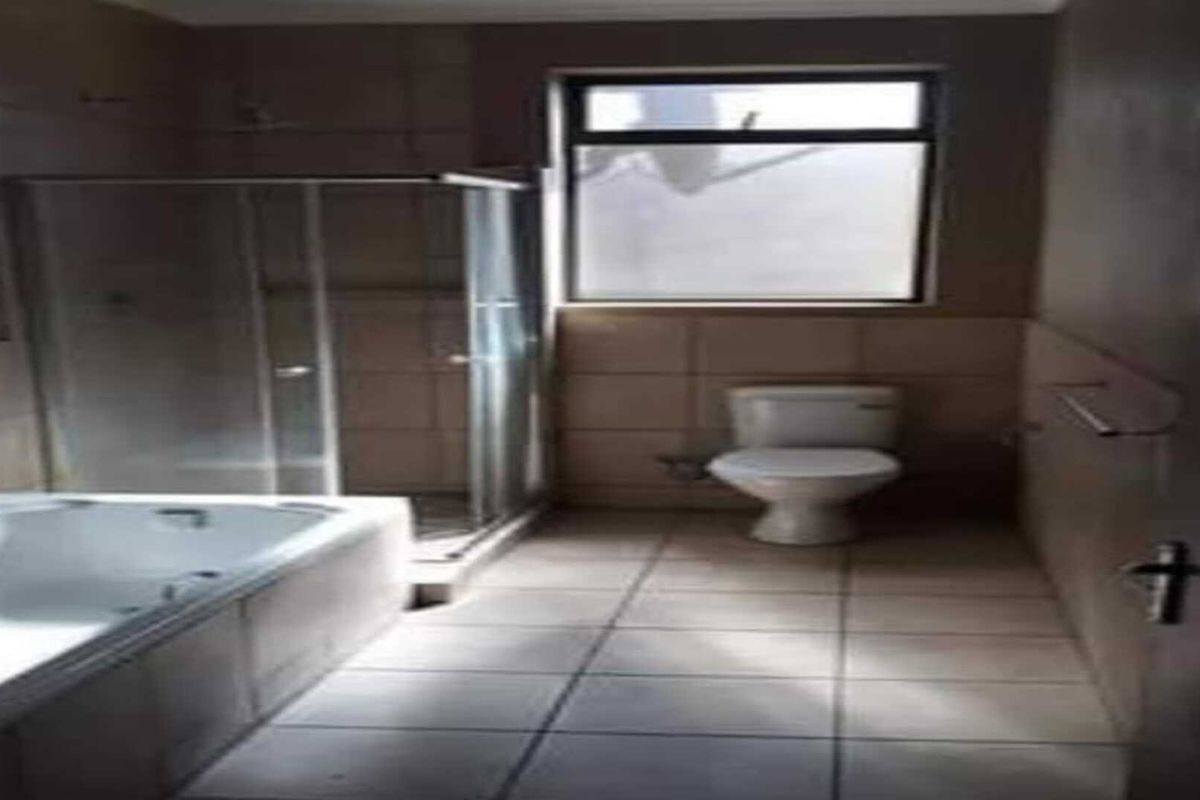 A functional bathroom featuring a bathtub, a separate glass-enclosed shower, and a toilet with neutral wall and floor tiling.