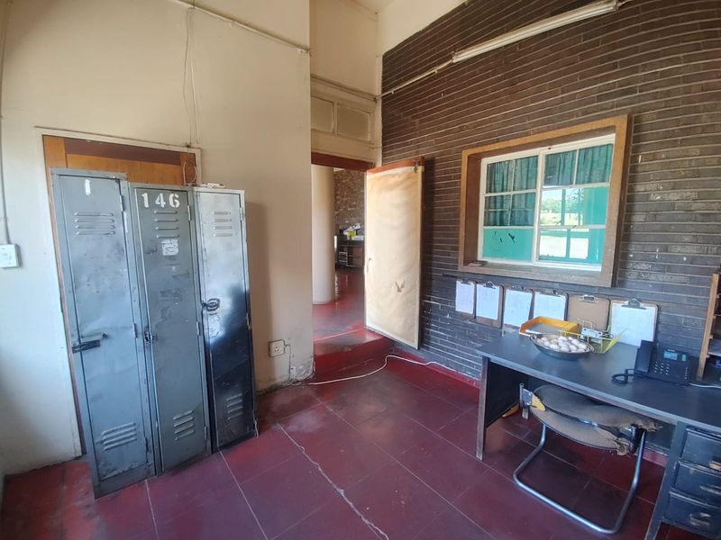 Industrial office or utility space featuring exposed brick walls, red tiled flooring, and built-in metal lockers.