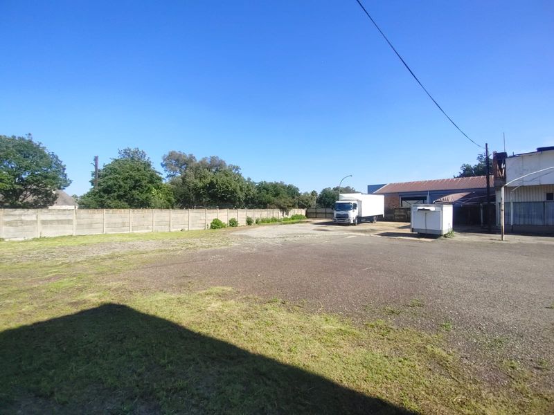 A spacious industrial yard featuring a large paved area, perimeter concrete walling, and access to warehouse facilities.