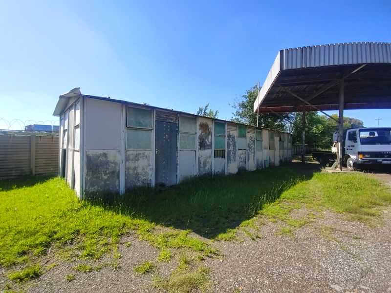 Exterior view of a modular industrial structure showing significant weathering and wear on the exterior cladding and window frames.