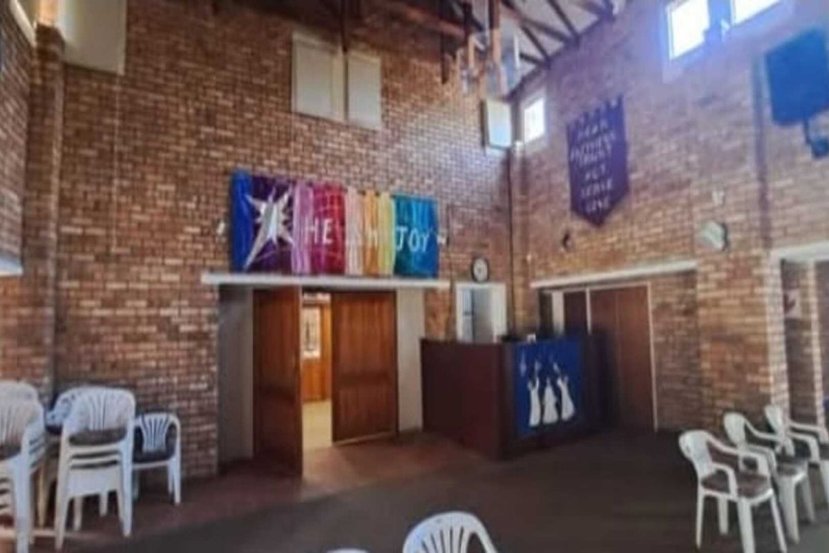 Spacious commercial hall featuring exposed brick walls, high vaulted ceilings, and multiple access points, suitable for community or event use.