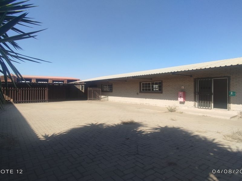 Rear exterior view of an industrial property featuring a paved yard, brick facade, and secure access points.