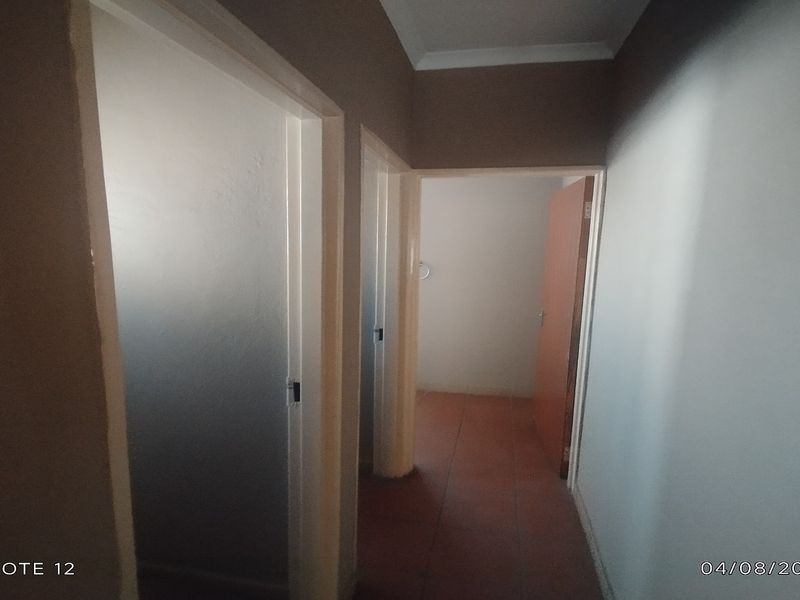 A simple interior hallway featuring tiled flooring and multiple internal doorways providing access to adjacent rooms.
