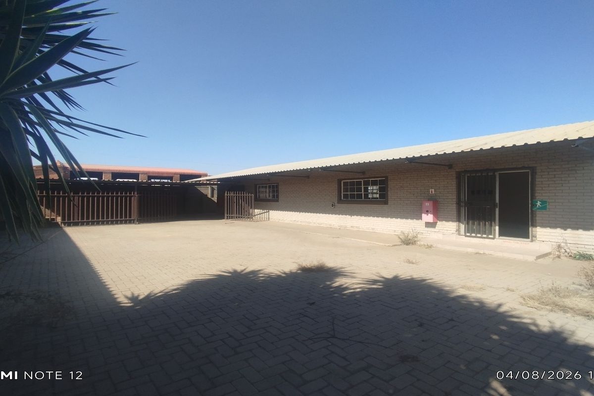 Rear exterior view of an industrial property featuring a paved yard, brick facade, and secure access points.