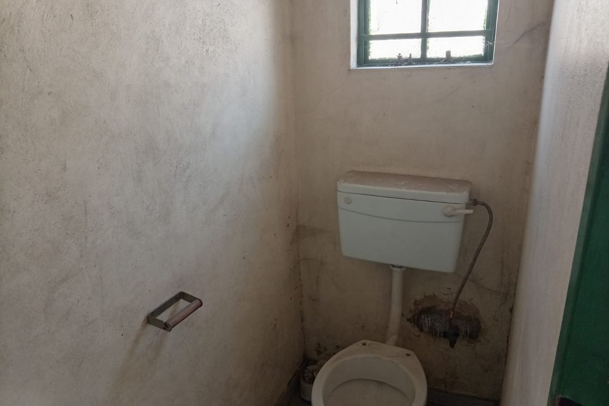 A small, dated bathroom featuring a standard toilet and cistern, requiring significant refurbishment and cosmetic updates to improve its condition.