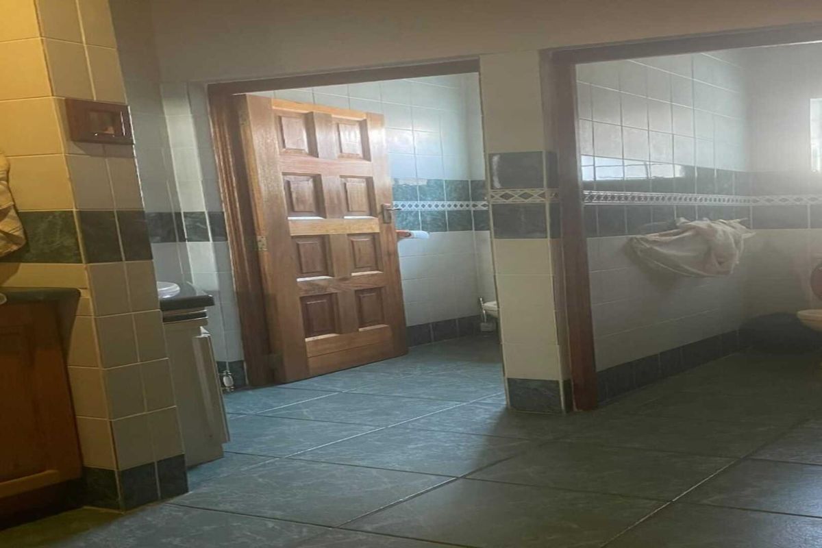A dated bathroom featuring ceramic wall and floor tiles, a wooden door, and a standard toilet setup.