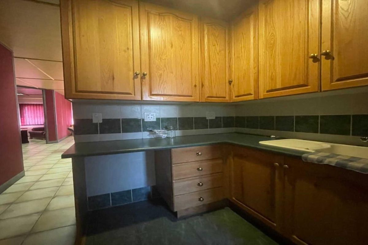 A functional kitchen area featuring traditional wooden cabinetry, tiled backsplash, and a laminate countertop, offering a blank canvas for modern renovation.