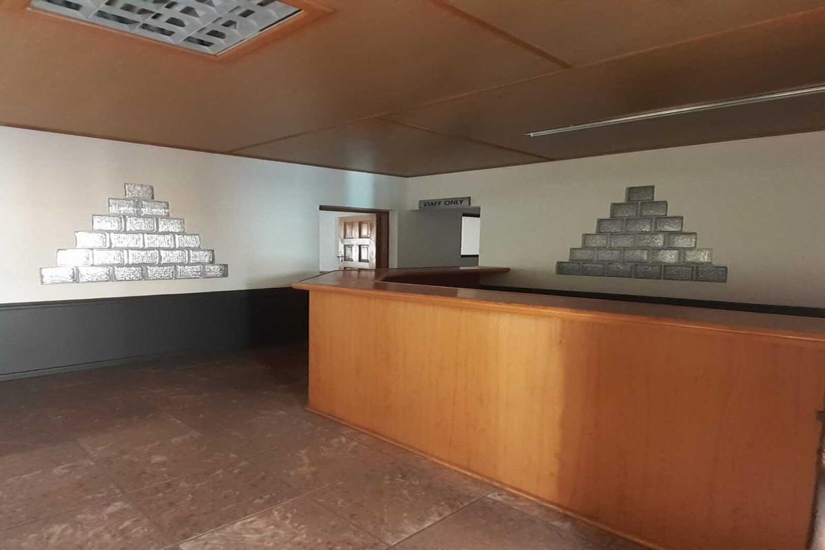 An empty office space featuring a built-in reception counter, decorative glass block wall accents, and tiled flooring, suitable for a professional workspace.