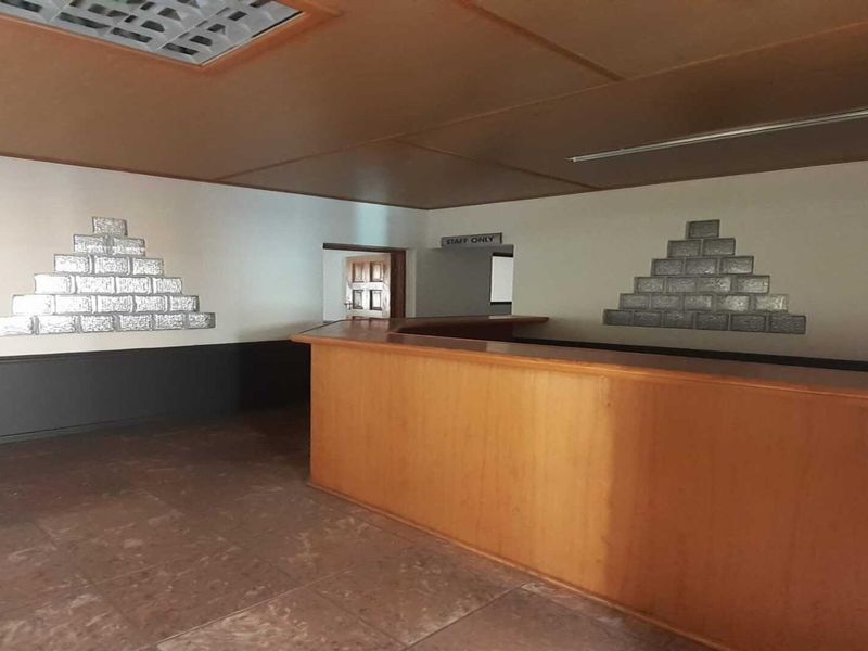 An empty office space featuring a built-in reception counter, decorative glass block wall accents, and tiled flooring, suitable for a professional workspace.