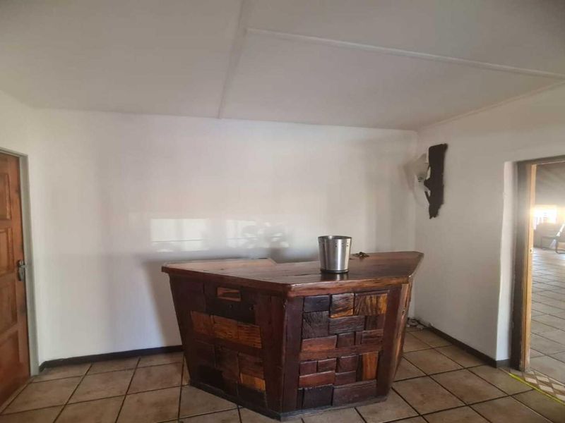 A dedicated bar area featuring a rustic built-in wooden counter, tiled flooring, and direct access to adjacent spaces.