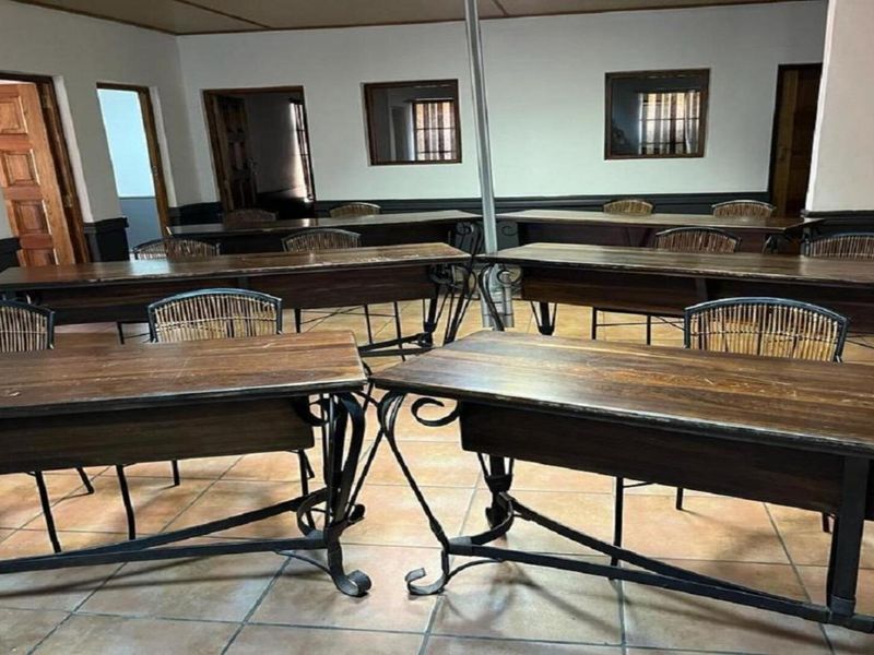 A functional office space featuring tiled flooring, built-in wooden cabinetry, and multiple workstations, suitable for a professional work environment.