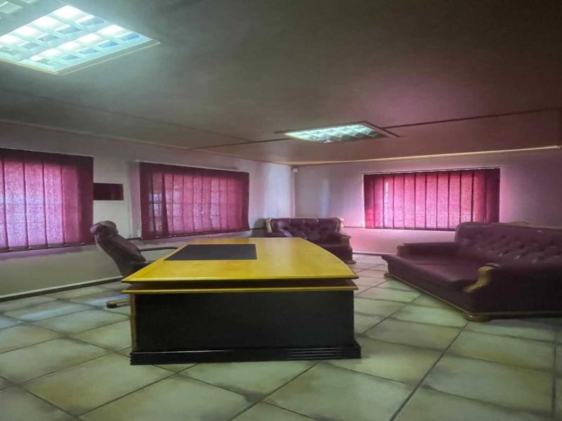 A functional office space featuring tiled flooring, recessed ceiling lighting, and vertical window blinds, providing a practical environment for professional use.