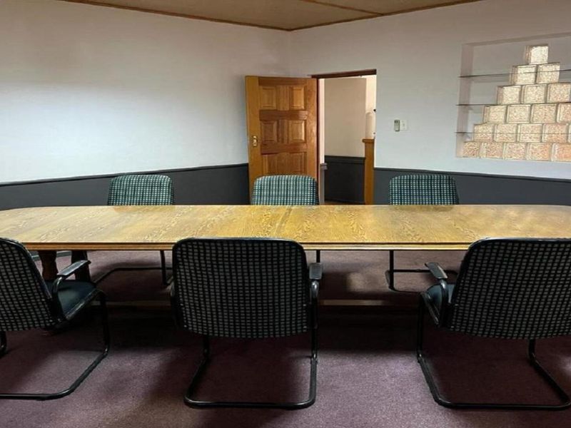 A functional office meeting room featuring a large boardroom table, wainscoting, and a decorative glass block feature wall.